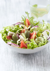 Salad with Green Olives, Tomatoes and Feta Cheese. Bright wooden background.