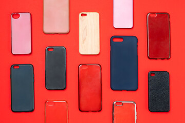 Pile of multicolored plastic back covers for mobile phone. Choice of smart phone protector accessories on red background. A lot of silicone phone backs or skins next to each other