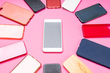 Choice of multicolored plastic back covers for mobile phones on pink background with a smart phone on the side