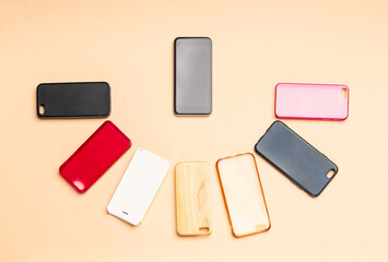Choice of multicolored plastic back covers for mobile phones on neutral background with a smart phone on the side