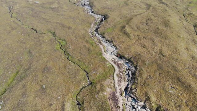 Aerial footage of Isle of Skyes most iconic location, the Fairy Pools captured at foot of Cullin mountain range this shot captures the meandering river beyond the Scottish Highlands.