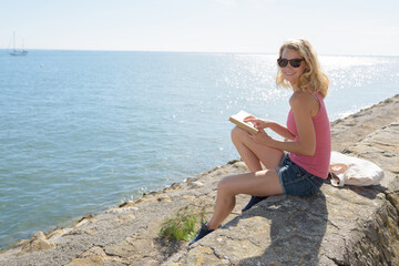 young woman reading book on the sea beach