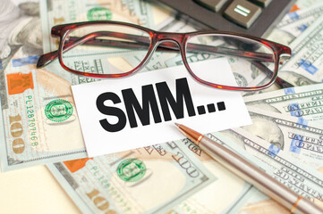 On the table are bills, a bundle of dollars and a sign on which it is written - SMM. Business and Finance concept.