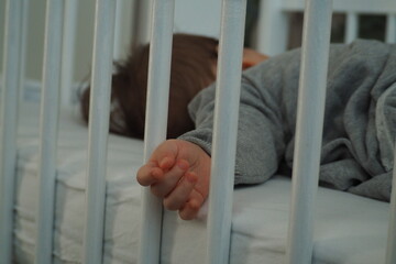 Ręka dziecka przesunięta przez słupki łóżka