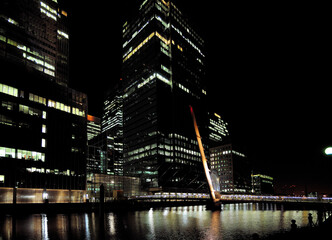 View To The South Quay Footbridge At South Dock In Front Of The Brightly Lit Bank Towers Of Canary...