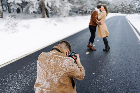 fot&oacute;grafo haciendo fotos a una pareja en una carretera de monta&ntilde;a en d&iacute;a de invierno con mucha nieve