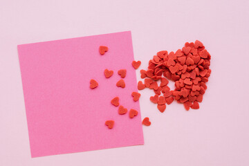 Red heart from red sugar hearts and piece of pink paper on pink background. Valentine's day background. Backspace.