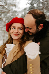 pareja joven abrigada feliz abrazándose en el exterior en bosque en un día frio de invierno