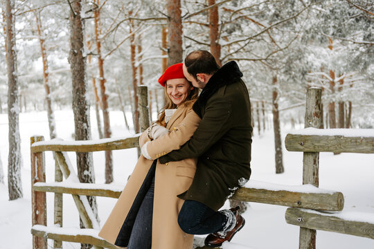 pareja joven abrigada feliz abrazándose en el exterior en bosque en un día frio de invierno