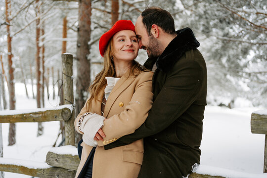 pareja joven abrigada feliz abraz&aacute;ndose en el exterior en bosque en un d&iacute;a frio de invierno