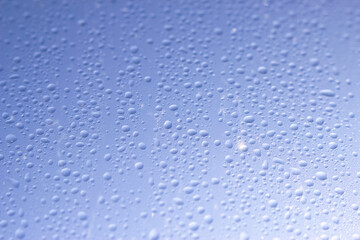 wet window with water drops and blue sky - close up in sunny day, water background