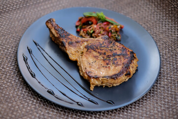 grilled steak on the bone on a blue plate on a wooden table