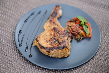 grilled steak on the bone on a blue plate on a wooden table