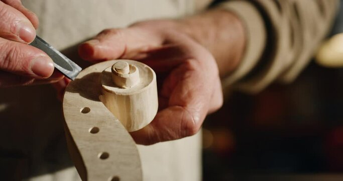 Cinematic macro of experienced master artisan luthier painstaking detail work on fine quality wood violin in creative workshop.Concept of spiritual instrument,handmade, art, orchestra, artisan,passion