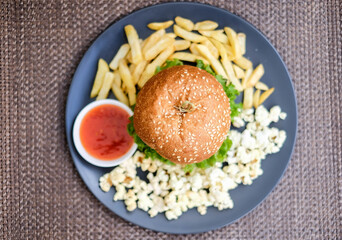 Fast food and unhealthy eating concept, french fries, ketchup and burger on the black plate