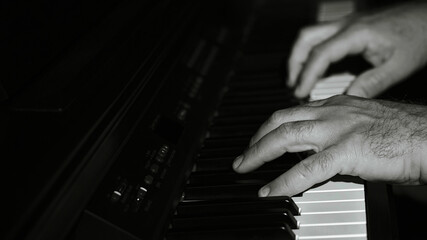 Manos de hombre de media edad tocando el piano, foto en blanco y negro