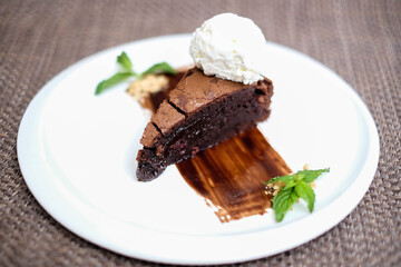 A slice of rich chocolate cake with a scoop of ice cream
