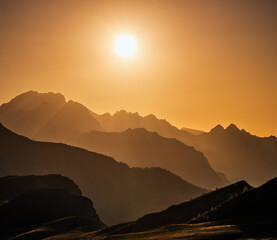 Sun glow in evening hazy sky and mountain silhouettes view