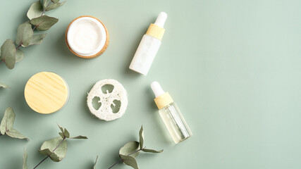 Set of herbal cosmetic and eucalyptus leaves on green background. Jar of moisturizer cream, facial...