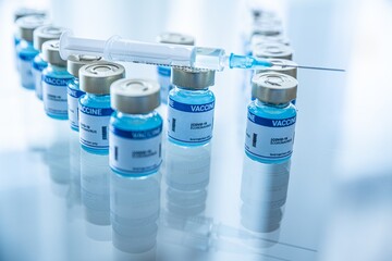 Ampoules with Covid-19 vaccine and syringe with needle on a laboratory bench. To fight the coronavirus. Pandemic time.