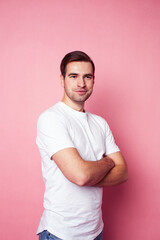 young caucasian guy in white t-shirt posing cheerful on pink background, lifestyle people concept