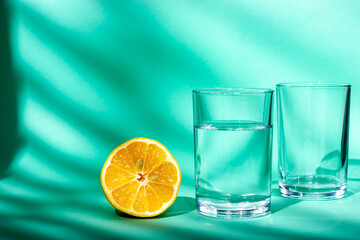 A glass of drinking water and half a fresh lemon. Water in a glass. Sunlight from the window.