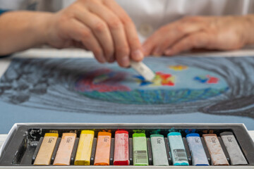 Fototapeta premium Paris, France - 31 01 2021: Details of the hands of a woman artist drawing and colored chalks
