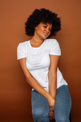 pretty young african american woman with curly hair posing cheerful gesturing on brown background, lifestyle people concept