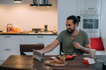 A man is having breakfast at home with a tablet.