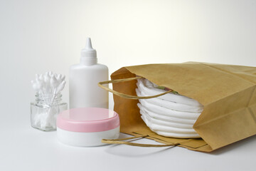 Diapers and hygiene products in a paper bag on a light background. Disposable baby panties.