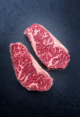 Raw dry aged wagyu roast beef steak offered as top view on a black board with copy space