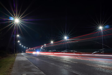 Fototapeta na wymiar Car light trail and city light. Night shot. Vehicle back lights illumination on highway