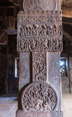 Bagalakote, Karnataka, India - November 7, 2013: Pattadakal temple complex. Closeup of gray stone pillar with sculpted teaching and dancing scenery, Virupaksha temple.