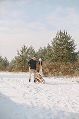 Family in knitted winter hats on family Christmas vacation. Parents and little girl in a park. People walks.