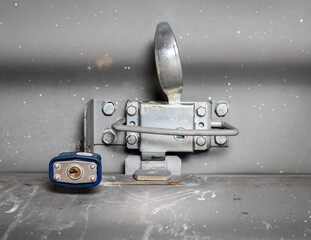Roof hatch closure with lock on ceiling, closeup. Secured roof access for maintenance roof of homes and buildings. Textured grey walls. Selective focus.