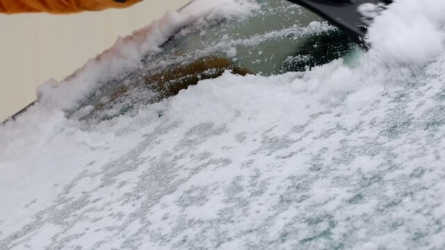 cleaning icy frozen windshield after a snow storm in winter