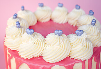 Exquisite Valentine's Day cake decorated with pink icing with heart-shaped candies on top.