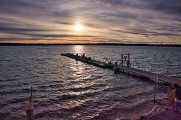 Obraz premium Langer Anlegesteg aus Holz am Markkleeberger See bei Sonnenuntergang im Winter mit Blick über das glitzernde Wasser zum Horizont, Markkleeberg, Sachsen, Deutschland