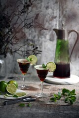 Alcoholic cocktail with lime and ice on wooden table
