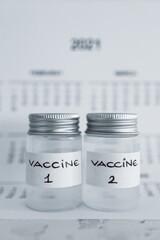 covid-19 vaccine against the pandemic, ampoules with Vaccine 1 and Vaccine 2 labels side by side next to 2021 yearly calendar