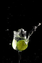 Fototapeta na wymiar Lemon lime slice falling into glass cup with water, splash effect