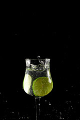 Lemon lime slice falling into glass cup with water, splash effect