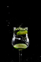 Lemon lime slice falling into glass cup with water, splash effect