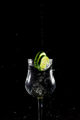 Lemon lime slice falling into glass cup with water, splash effect