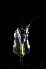 Lemon lime slice falling into glass cup with water, splash effect