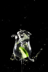 Lemon lime slice falling into glass cup with water, splash effect