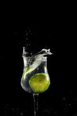 Lemon lime slice falling into glass cup with water, splash effect