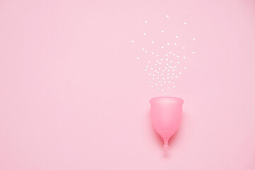 Menstrual cup with glitter on pink background. Alternative feminine hygiene product during the period. Women health concept