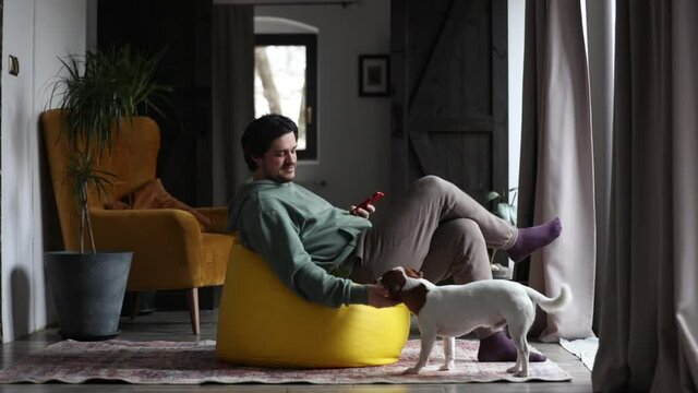 man working on outsource with laptop and playing with dog in same time at home