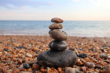 Fototapeta na wymiar beautiful balance of stones on the sandy beach of the ocean, on a background of bright sky